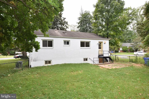 a view of a white house with a big yard and sitting area