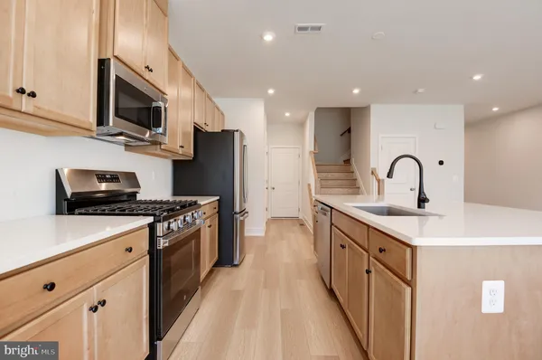 a kitchen with stainless steel appliances granite countertop a white cabinets a sink a stove a dining table and chairs