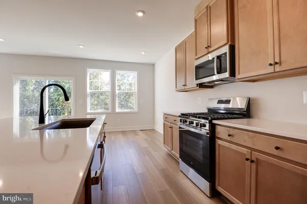 a kitchen with granite countertop a stove a sink a refrigerator and wooden floor