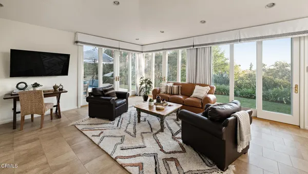 a living room with furniture a flat screen tv and a floor to ceiling window
