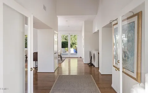 a view of a hallway with wooden floor and a bathroom