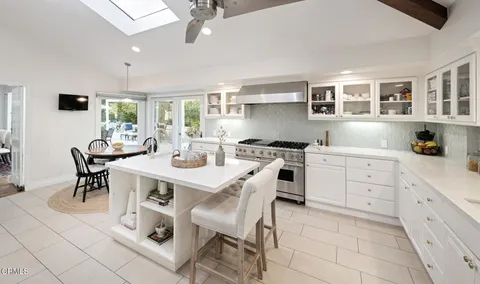 a kitchen with a dining table chairs cabinets and stainless steel appliances