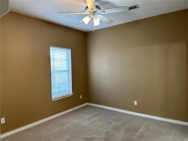 an empty room with a window and a ceiling fan