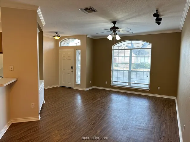 an empty room with wooden floor chandelier and windows