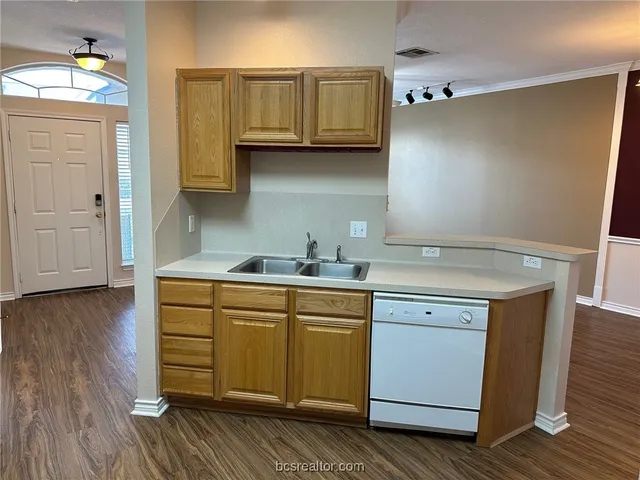 a kitchen with granite countertop a sink cabinets and wooden floor