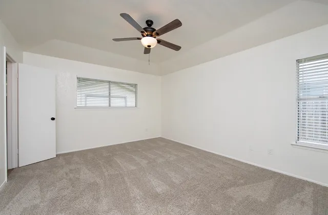 an empty room with windows and fan