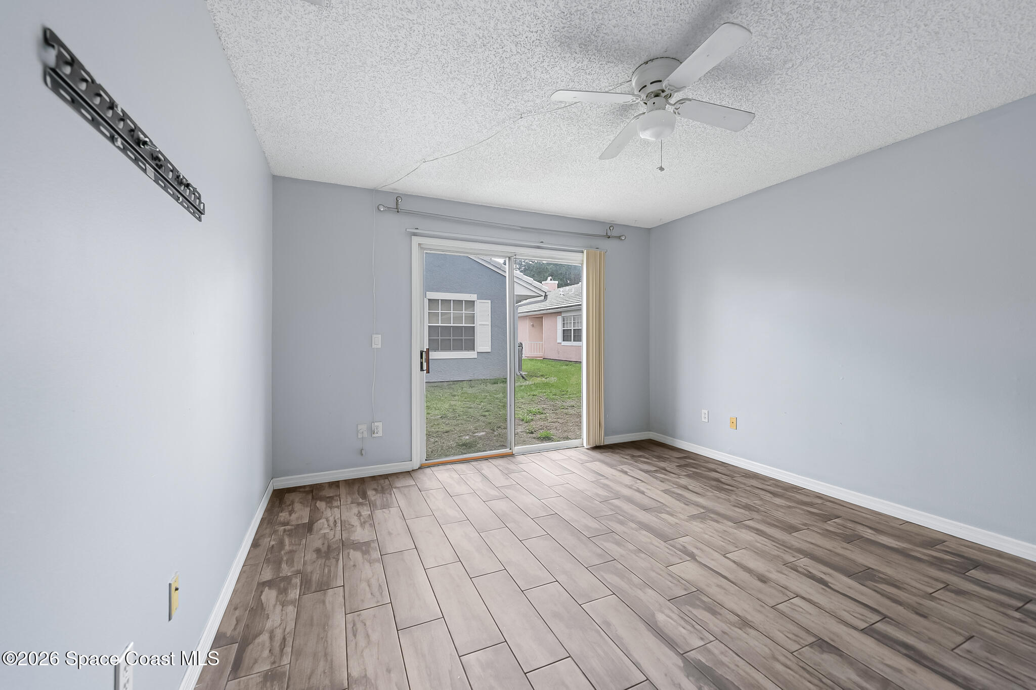 865 Dewberry Terrace Northeast Palm Bay, FL 32905 - Photo 8 of 29 a view of an empty room with a window and wooden floor
