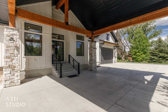 1188 South Old Trappers Loop Road Huntsville, UT 84317 - Photo 16 of 92 Covered entryway featuring board-and-batten siding, stone veneer accents, wood beams, and a concrete drive