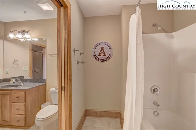 a bathroom with a granite countertop sink a toilet and shower