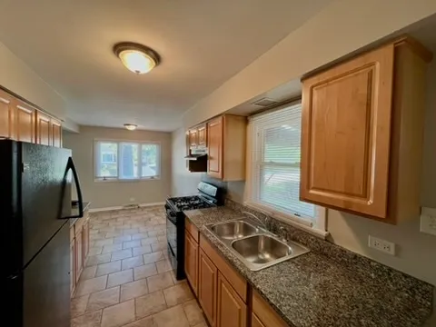 a kitchen with granite countertop a sink stove and refrigerator