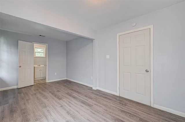 a view of an empty room with wooden floor & closet