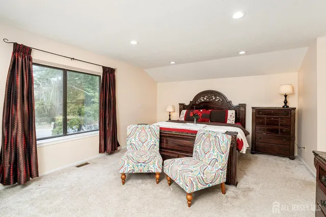 a bedroom with a bed a dresser and a large mirror