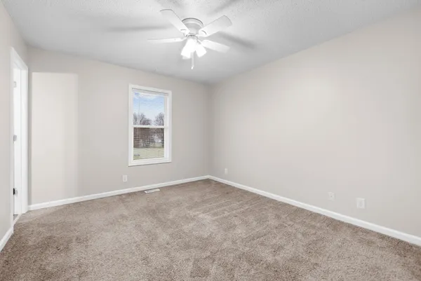 an empty room with windows and fan