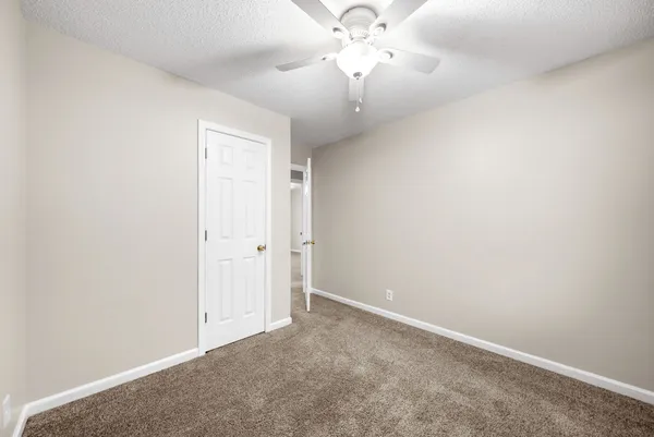 an empty room with a chandelier fan and a ceiling fan