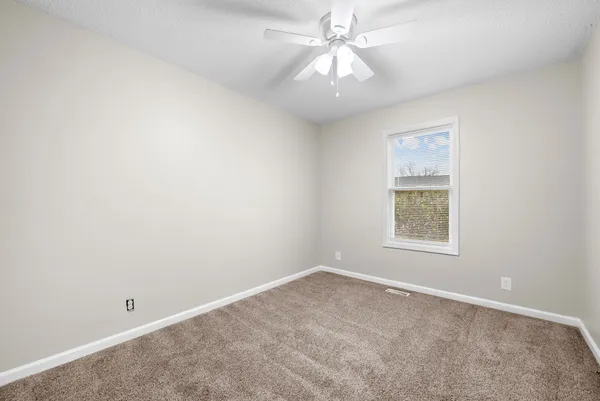 an empty room with a fan & a window