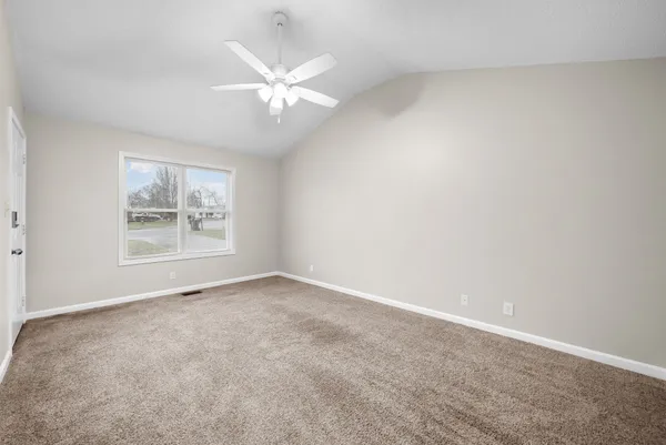 an empty room with windows and fan