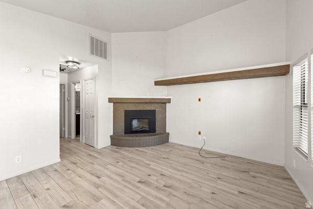 301 South 1200th Street East, Unit 31 St. George, UT 84790 - Photo 11 of 21 Unfurnished living room featuring light wood-type flooring, a glass covered fireplace, and a high ceiling