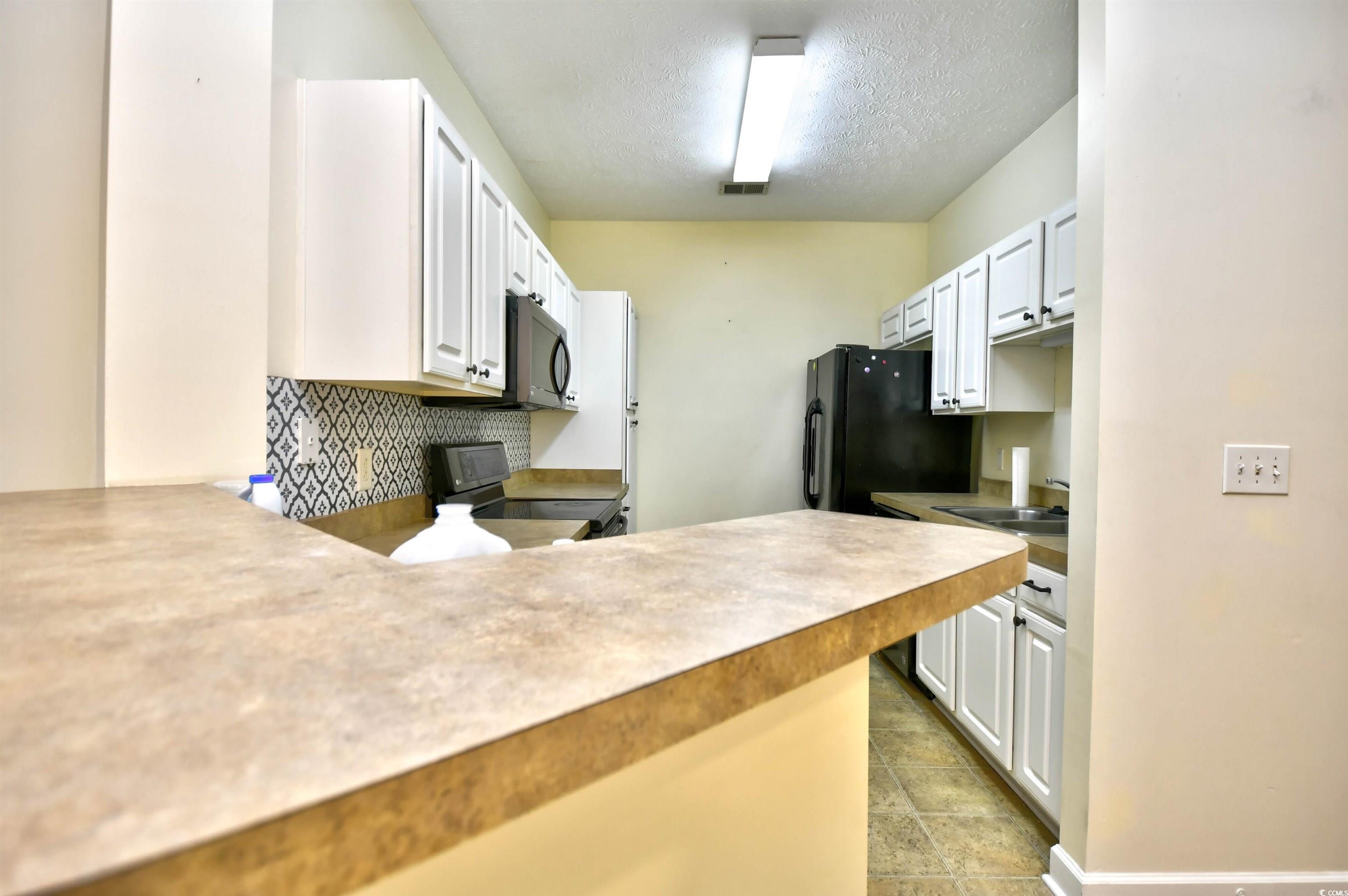 213 Wando River Road, Unit 11G Myrtle Beach, SC 29579 - Photo 8 of 30 Kitchen with pendant lighting, black refrigerator