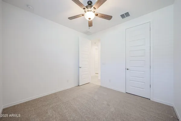 an empty room with closet and a ceiling fan