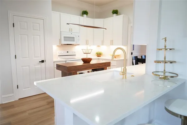 a kitchen with stainless steel appliances a sink a stove and white cabinets with wooden floor