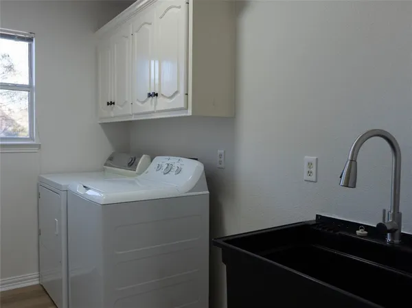 a utility room with sink dryer and cabinets