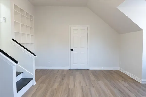 a view of an empty room with wooden floor and stairs