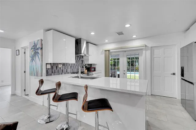 a kitchen with stainless steel appliances kitchen island granite countertop a refrigerator and a stove top oven with wooden floor