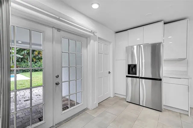 a view of a refrigerator in kitchen and an empty room