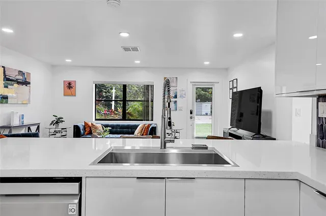 a kitchen with stainless steel appliances sinks a refrigerator and a large window