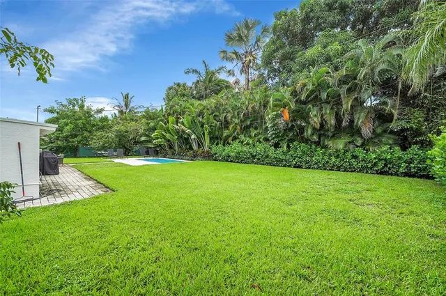a view of a white house with a big yard and potted plants