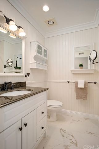 a bathroom with a granite countertop sink a toilet and a mirror