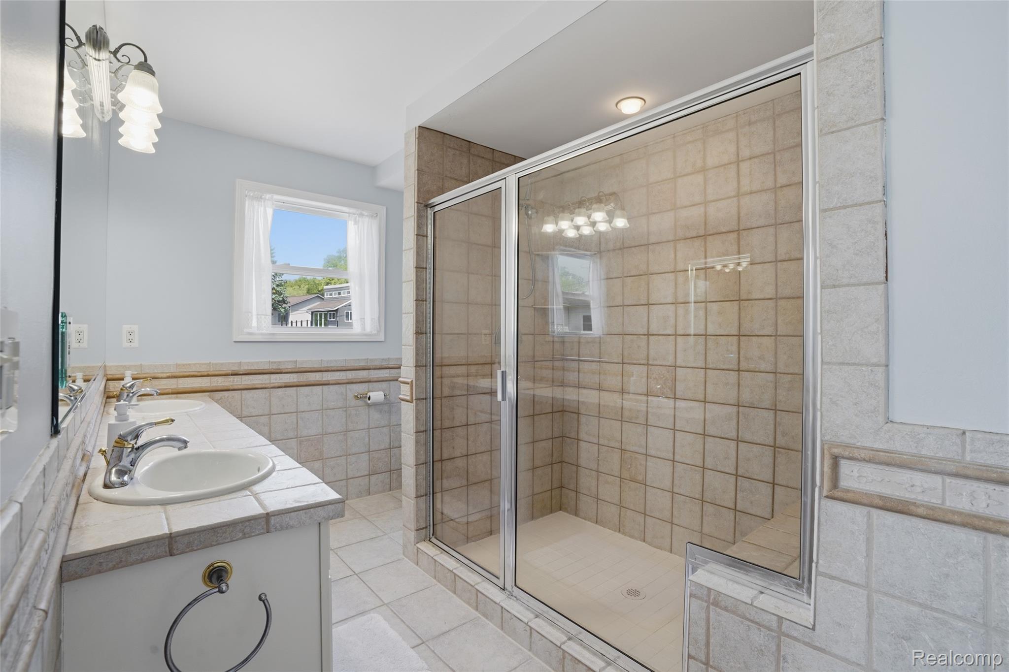 7217 Andersonville Road Clarkston, MI 48346 - Photo 28 of 65 Primary Bathroom featuring a glass-enclosed shower, dual vanity with undermount sinks, tiled countertop, and tiled flooring