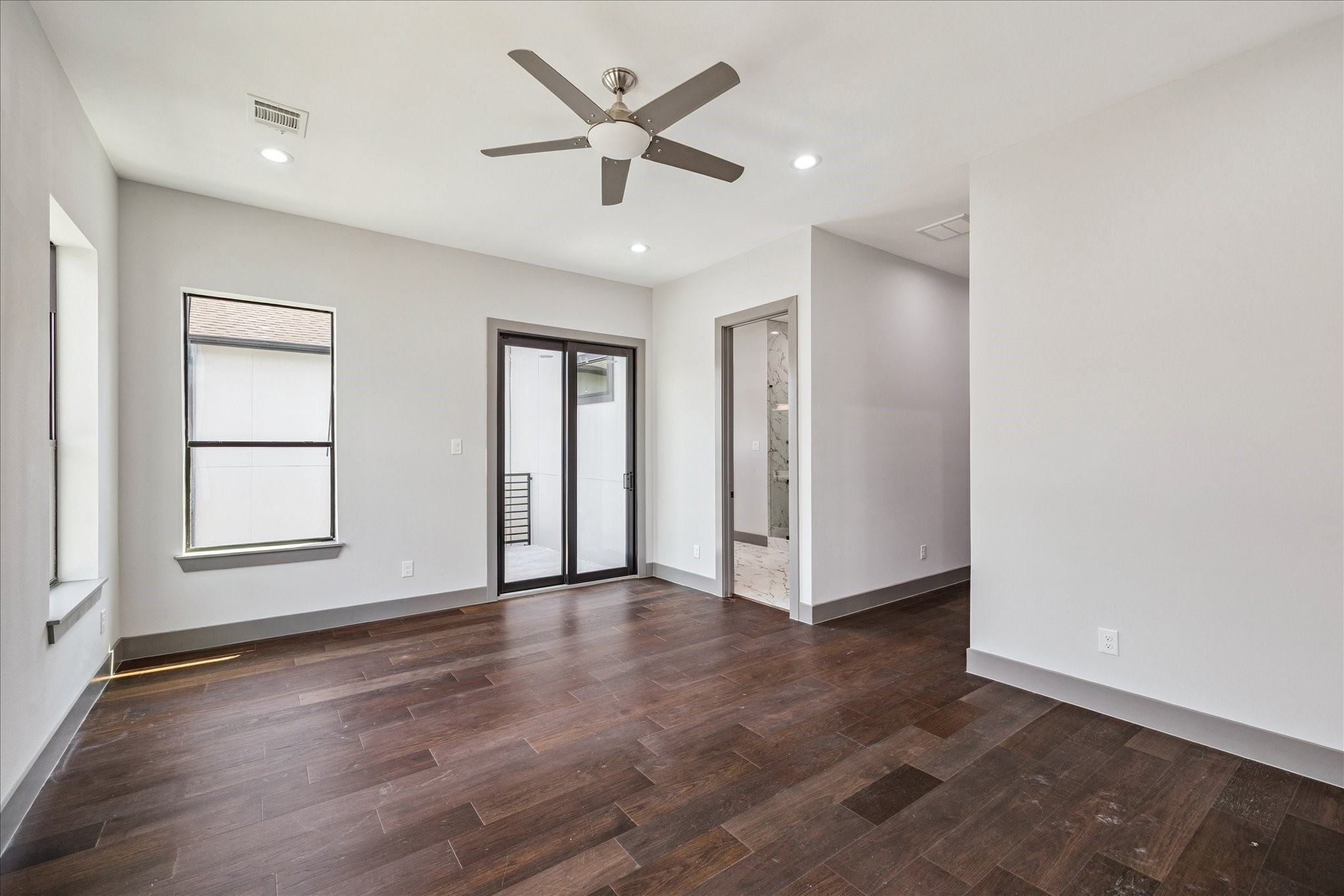 2319 Tuam Street Houston, TX 77004 - Photo 15 of 28 In the primary suite, elegant wood floors, recessed lighting, and a ceiling fan create comfort, while a sliding glass door opens to a private balcony and provides seamless entry to the en suite bathroom.