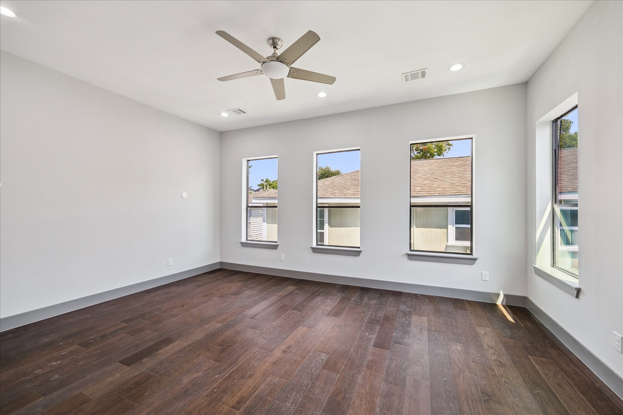 2319 Tuam Street Houston, TX 77004 - Photo 16 of 28 Spacious and inviting, the primary bedroom showcases wood floors, recessed lighting, and large windows that flood the room with natural light, creating a serene retreat.