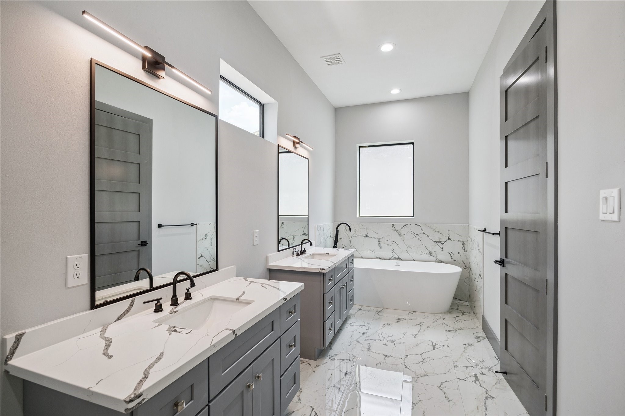 2319 Tuam Street Houston, TX 77004 - Photo 18 of 28 Designed with both style and function, the primary bath offers dual vanities, a frameless shower, and a tub positioned beneath natural light. Consistent tile finishes unify the space, while bold hardware provides a refined edge.