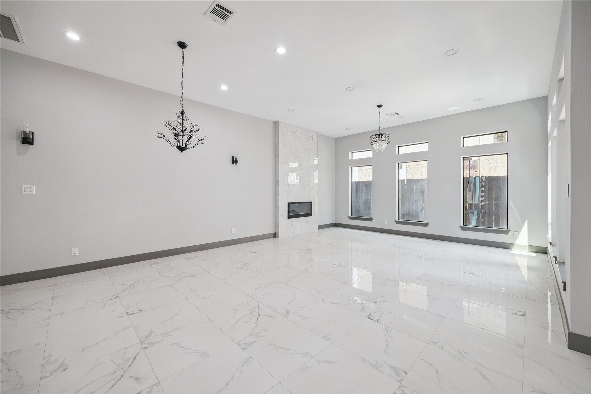 2319 Tuam Street Houston, TX 77004 - Photo 5 of 28 Living room is designed with a sense of openness and elegance, highlighted by its glossy marble-look tile floors that reflect natural light throughout the space. A sleek modern fireplace framed with floor-to-ceiling tile serves as the focal point, adding both style and warmth.
