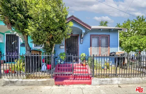 a view of house with a small yard and wooden fence