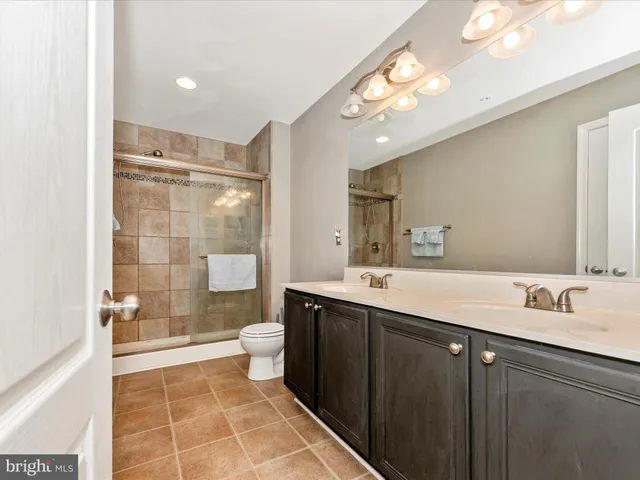 a bathroom with a double vanity sink mirror double shower and a toilet