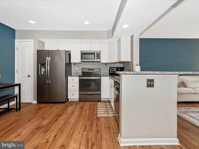a kitchen with kitchen island a refrigerator sink and wooden floor