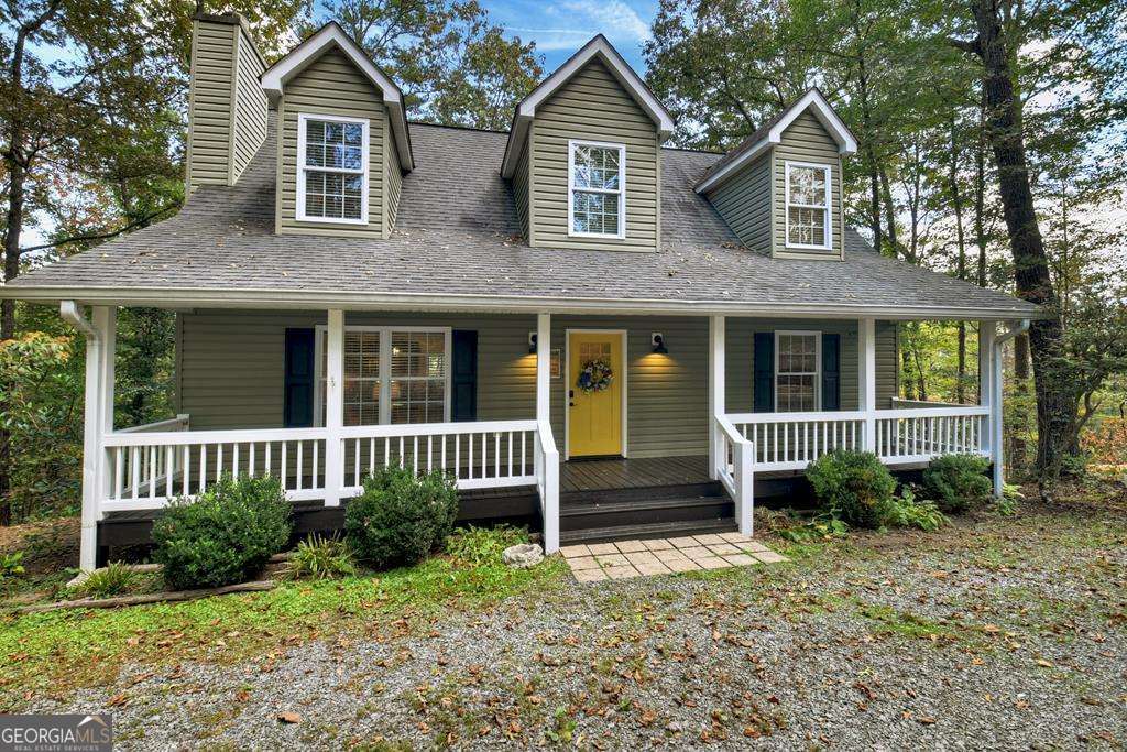 a view of a brick house with large windows and a yard with plants and large trees