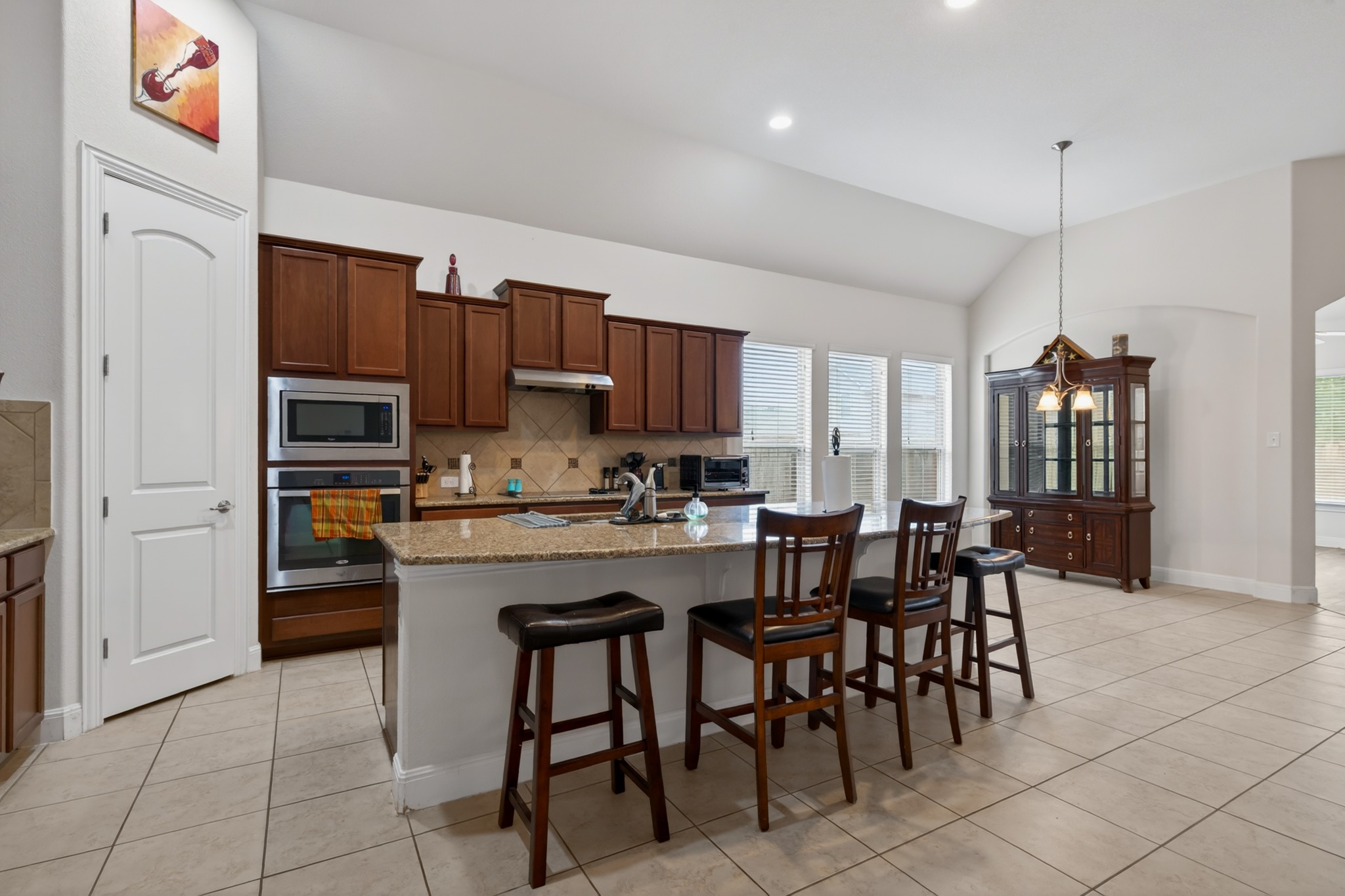 1017 Tabernash Leander, TX 78641 - Photo 6 of 38 Kitchen featuring a center island with bar seating, granite countertops, tile backsplash, stainless steel built-in oven and microwave, and wood-finish cabinetry