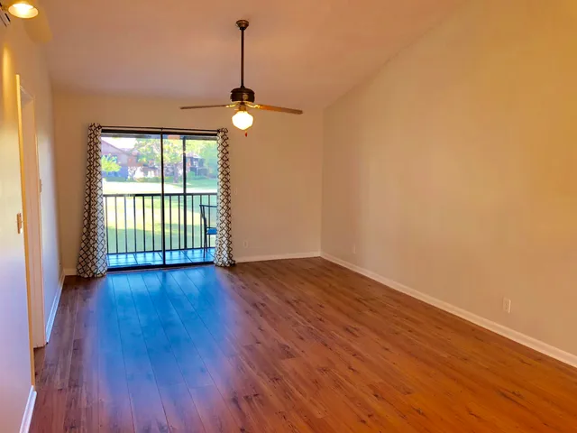 a view of empty room with wooden floor and fan