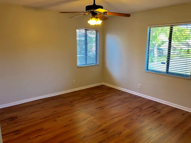 a view of an empty room with wooden floor and a window