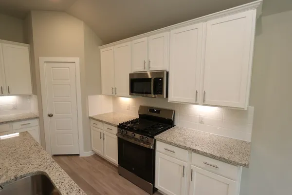 a kitchen with granite countertop white cabinets and stainless steel appliances