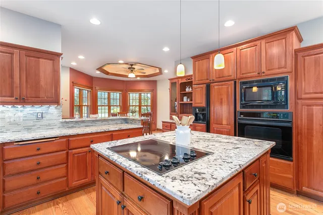 a kitchen with granite countertop a stove a sink a refrigerator and wooden cabinets