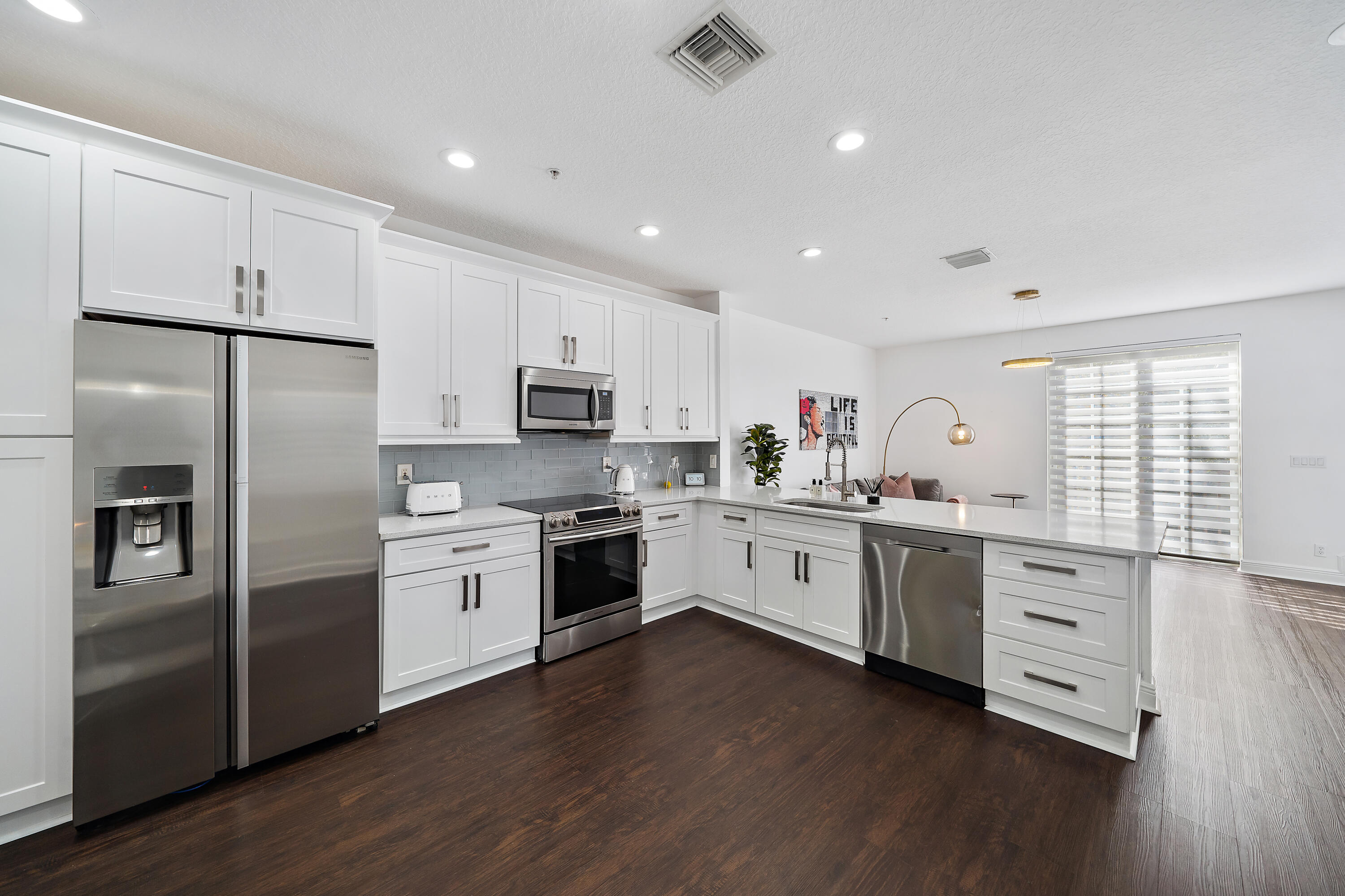 113 West Indian Crossing Circle Jupiter, FL 33458 - Photo 9 of 38 a kitchen with granite countertop white cabinets and stainless steel appliances