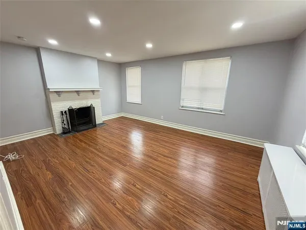 an empty room with wooden floor fireplace and windows