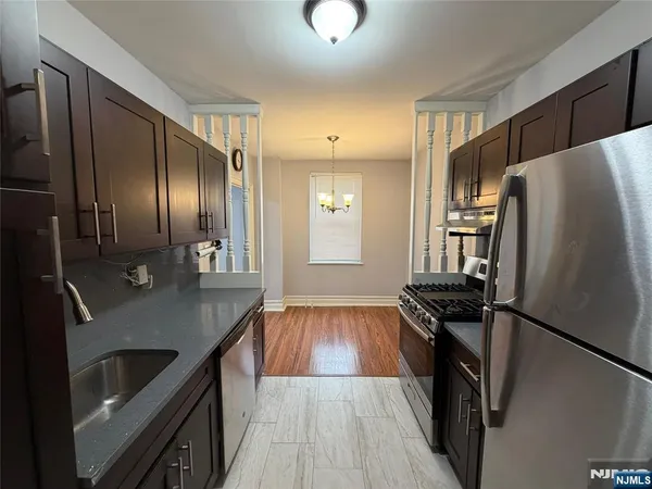 a kitchen with stainless steel appliances granite countertop a refrigerator a stove and a sink