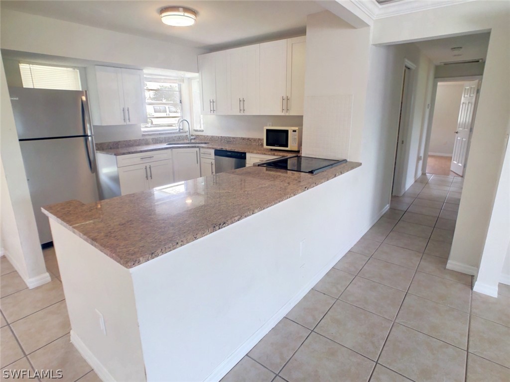 18577 Iris Road Fort Myers, FL 33967 - Photo 3 of 16 a kitchen with stainless steel appliances granite countertop a sink a microwave and a refrigerator