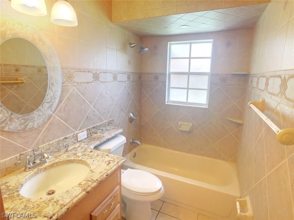18577 Iris Road Fort Myers, FL 33967 - Photo 6 of 16 a bathroom with a granite countertop sink a toilet and bathtub